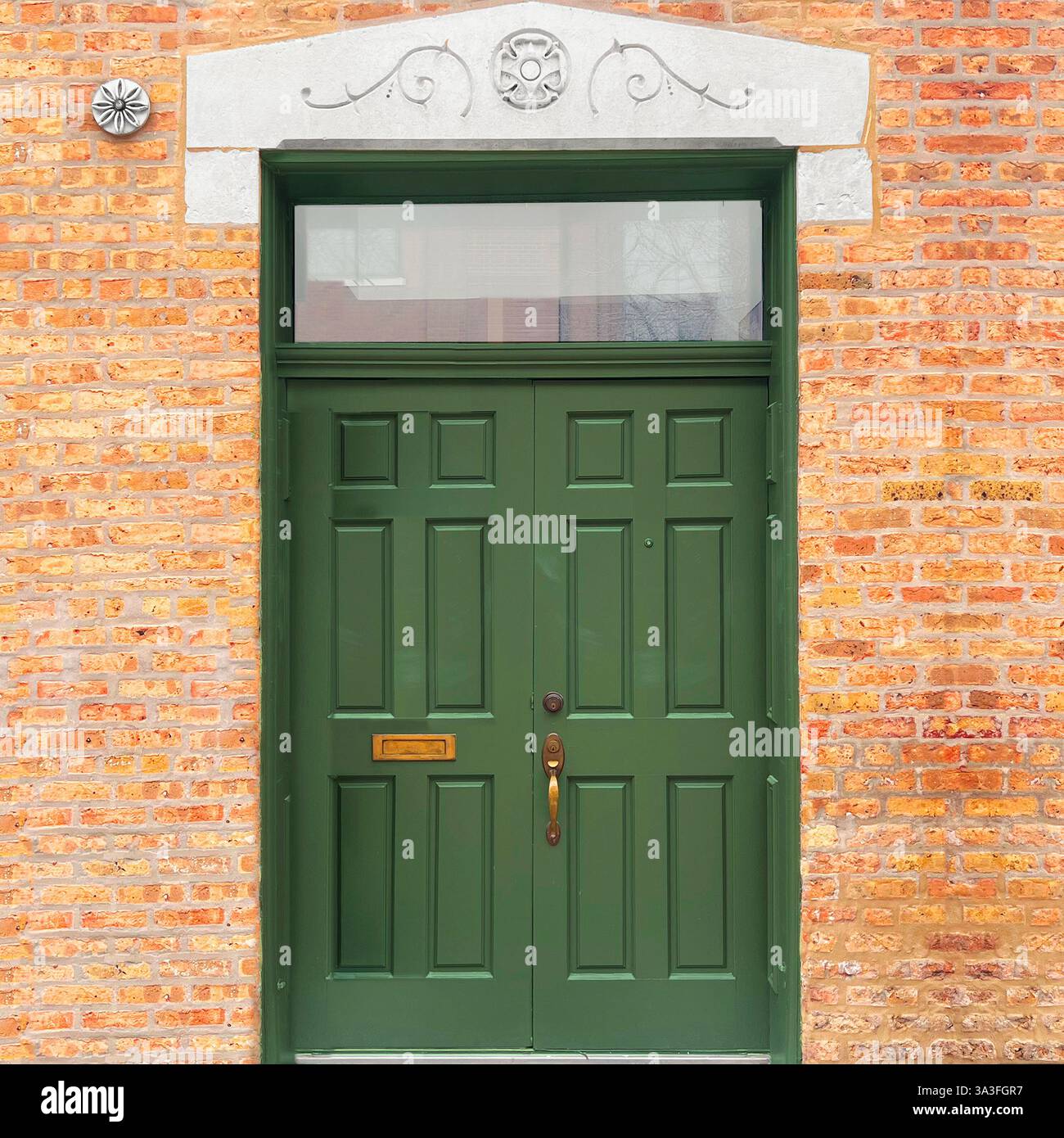 Portes vert olive avec fenêtre sur tableau arrière, linteau en pierre orné et façade en briques jaunes texturées à Chicago - Image de stock capturée avec un smartphone