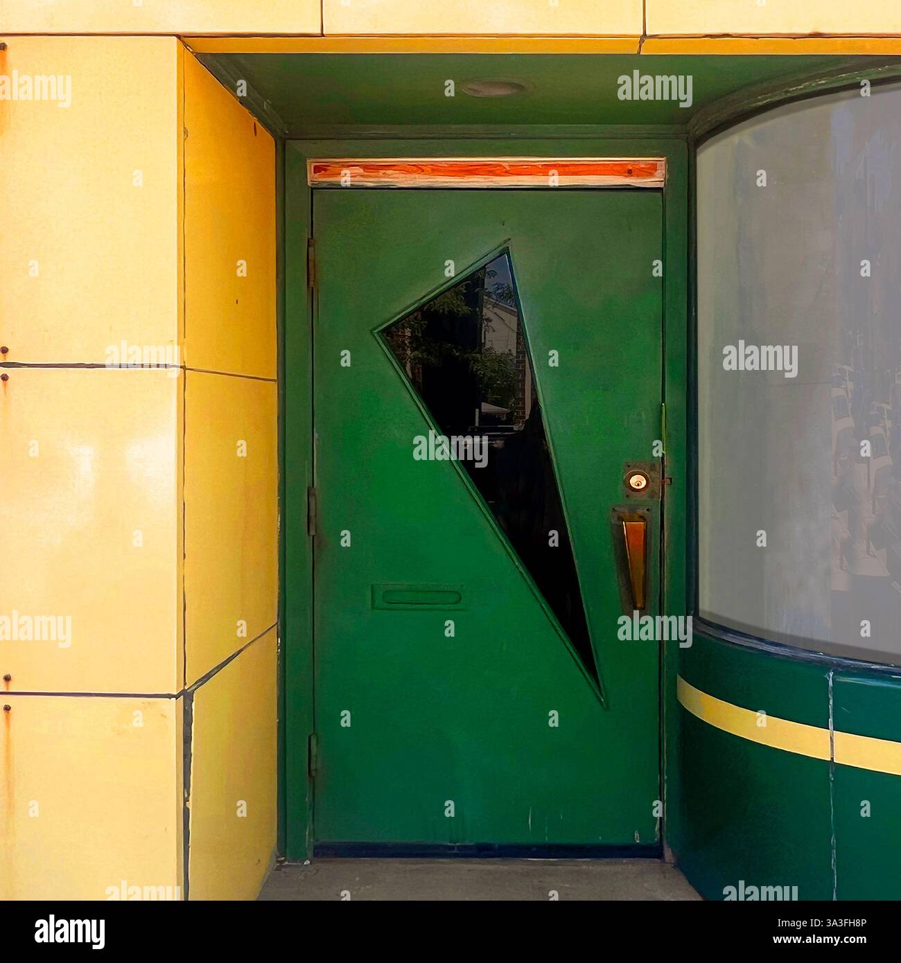 Une porte verte moderne du milieu du siècle avec une vitrine anguleuse audacieuse, située dans une façade carrelée jaune et verte à Chicago. Banque D'Images
