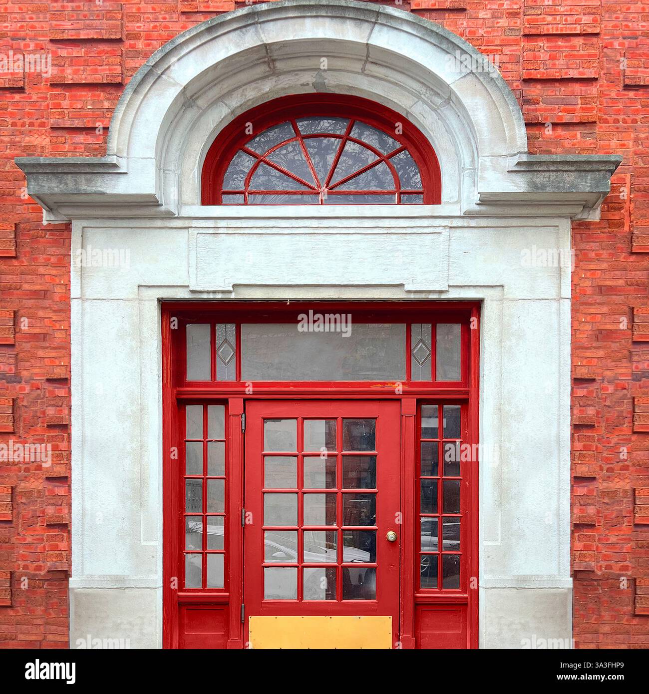 Élégante porte rouge de style français avec vitres et fenêtre cintrée, encadrée par une façade historique en briques et en pierre à Chicago. Banque D'Images