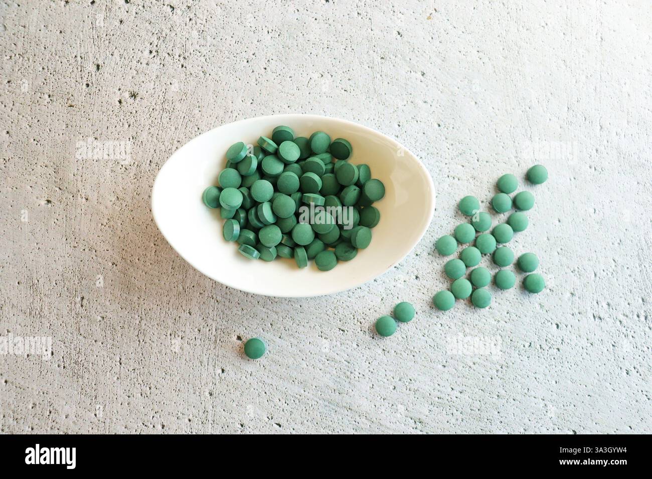 Pilules vertes spiruline ou algues chlorella dans le bol blanc. Chlorella d'orge verte. Banque D'Images