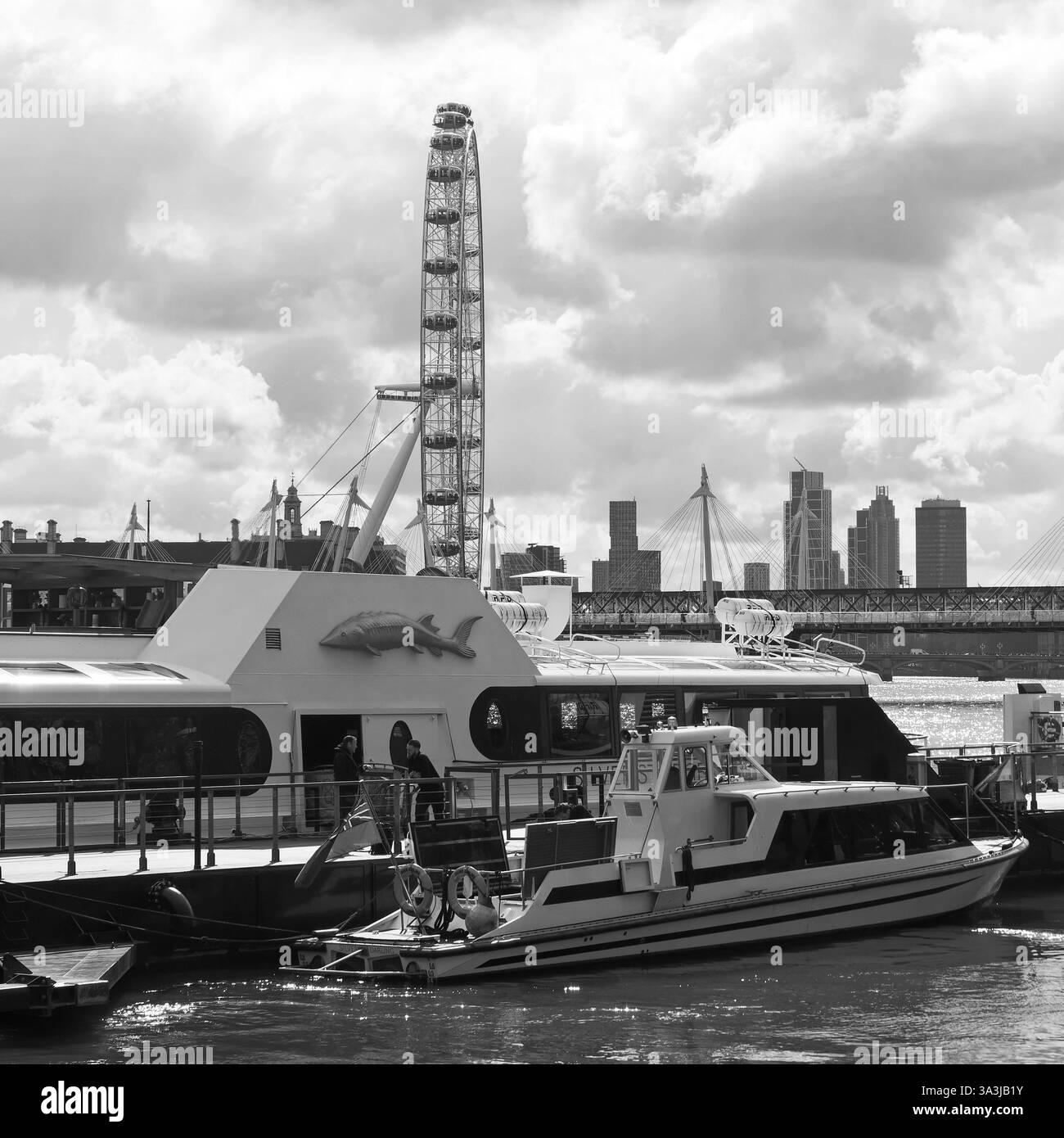 Bateaux et jetée sur la Tamise avec le London Eye à Londres, mars 2025. Monochrome Banque D'Images