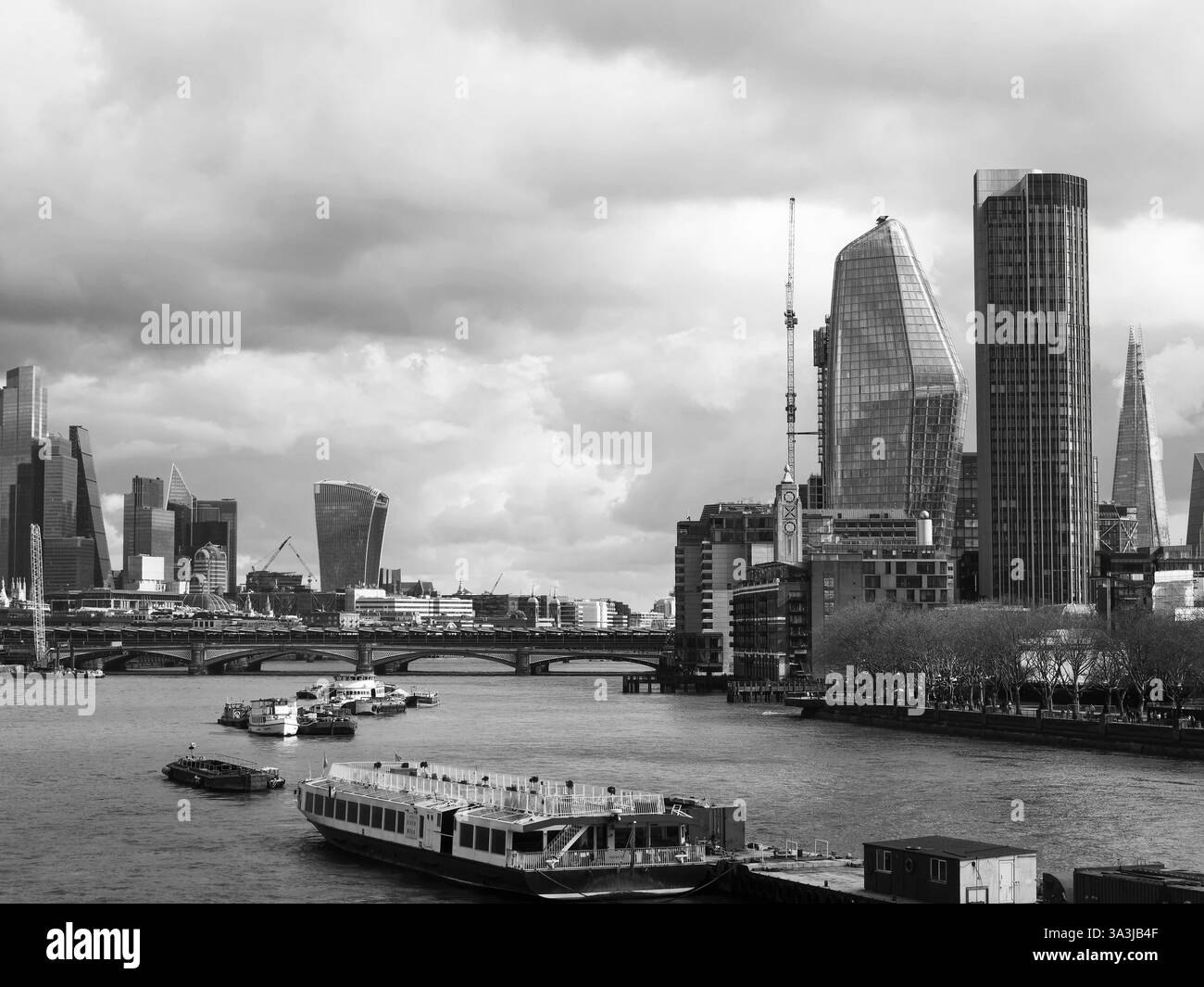 Sky Scrapers et Bridge enjambant la Tamise alors qu'un bateau attend sur une jetée. Shard tout à droite. Londres, mars 2025. Monochrome Banque D'Images