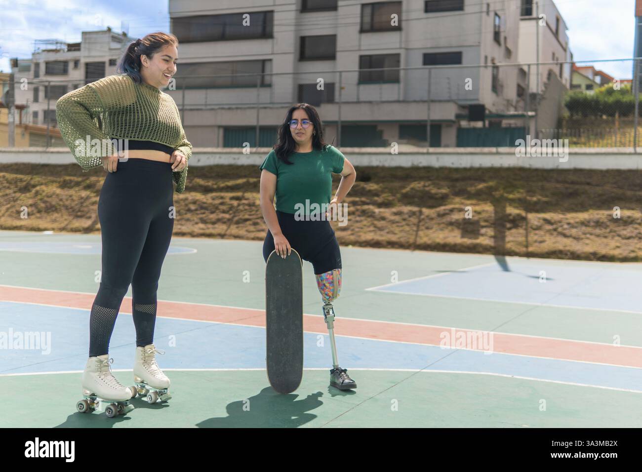 Deux amis, l'un avec une jambe prothétique et une planche à roulettes et l'autre avec des patins à roulettes, profitant d'une journée ensoleillée au skate Park Banque D'Images