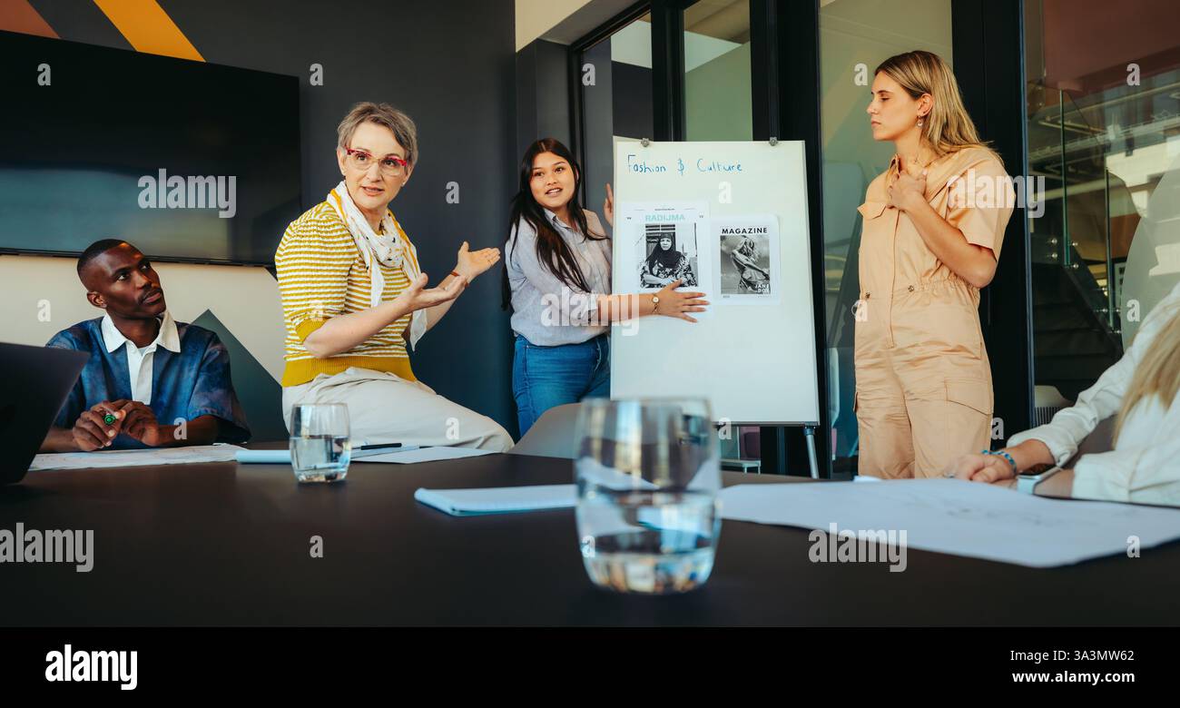 Un conférencier interagit avec une petite classe d'étudiants de premier cycle lors d'une présentation sur la mode et la culture, favorisant un environnement d'apprentissage engageant Banque D'Images