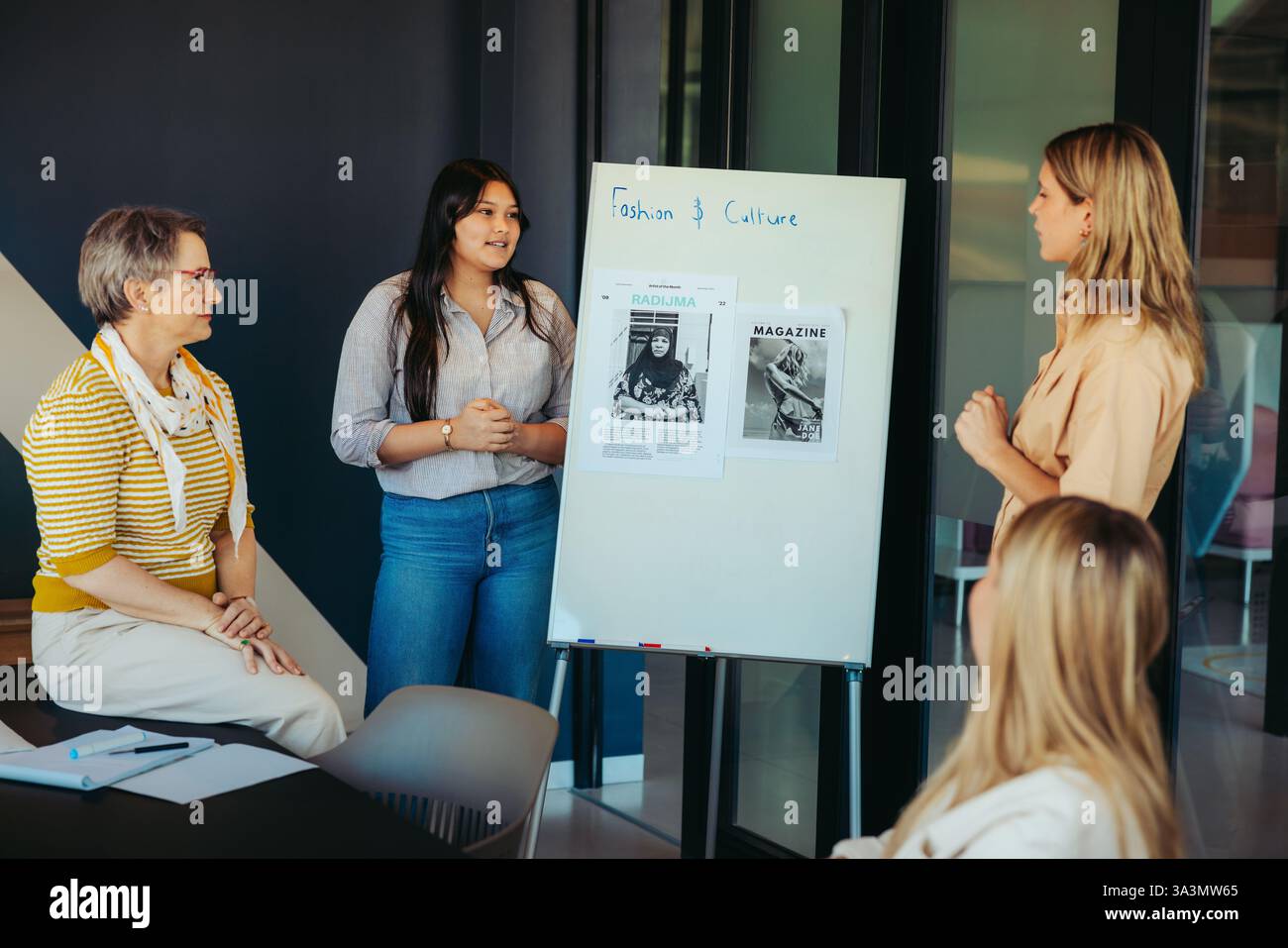 Des étudiantes présentant un projet de mode et de culture dans une salle de classe, mettant en valeur le travail d'équipe et la créativité. Banque D'Images