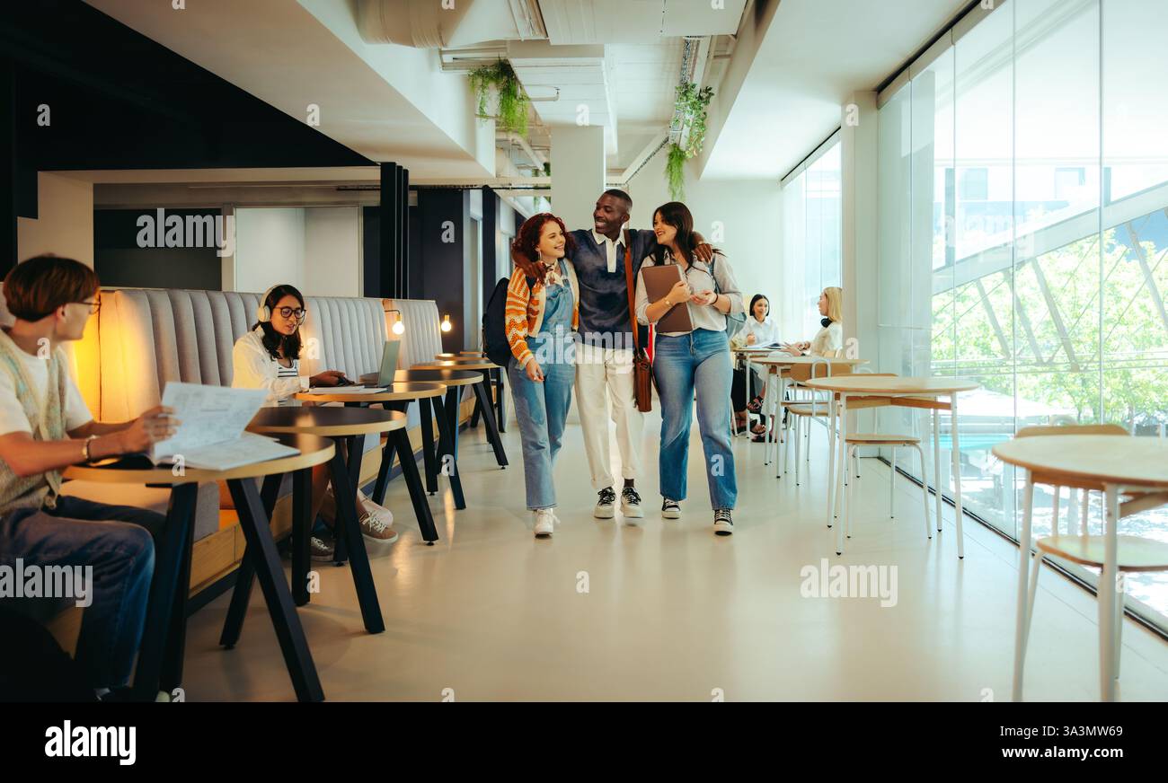 Un groupe diversifié d'amis d'université marchant ensemble dans un couloir de campus universitaire, soulignant l'amitié et l'atmosphère vibrante de la vie étudiante Banque D'Images