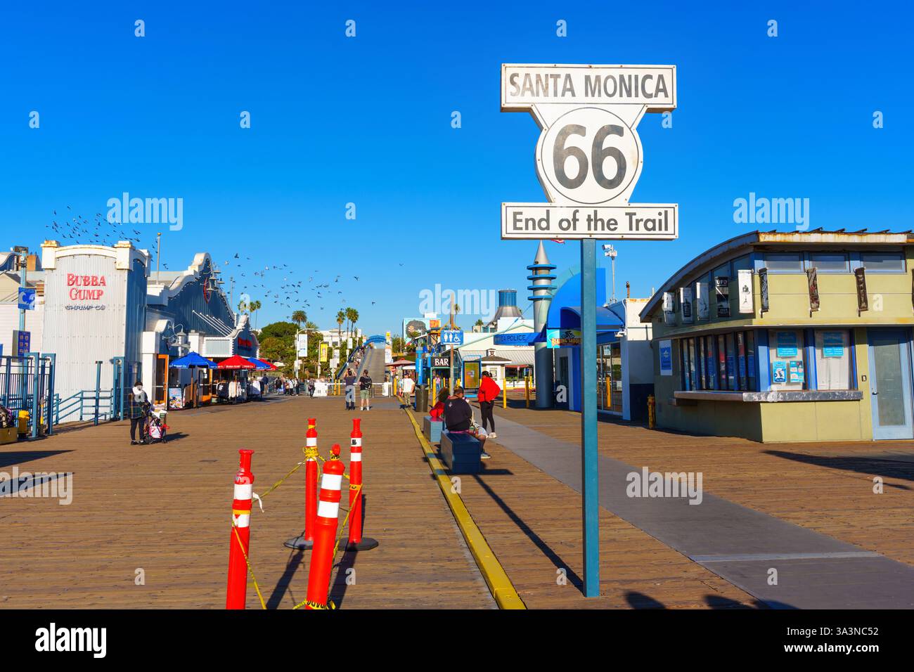 Santa Monica, Californie - 16 janvier 2025 : scène dynamique avec l'emblématique panneau de la route 66 à Santa Monica, Californie, avec des magasins et des foules Banque D'Images