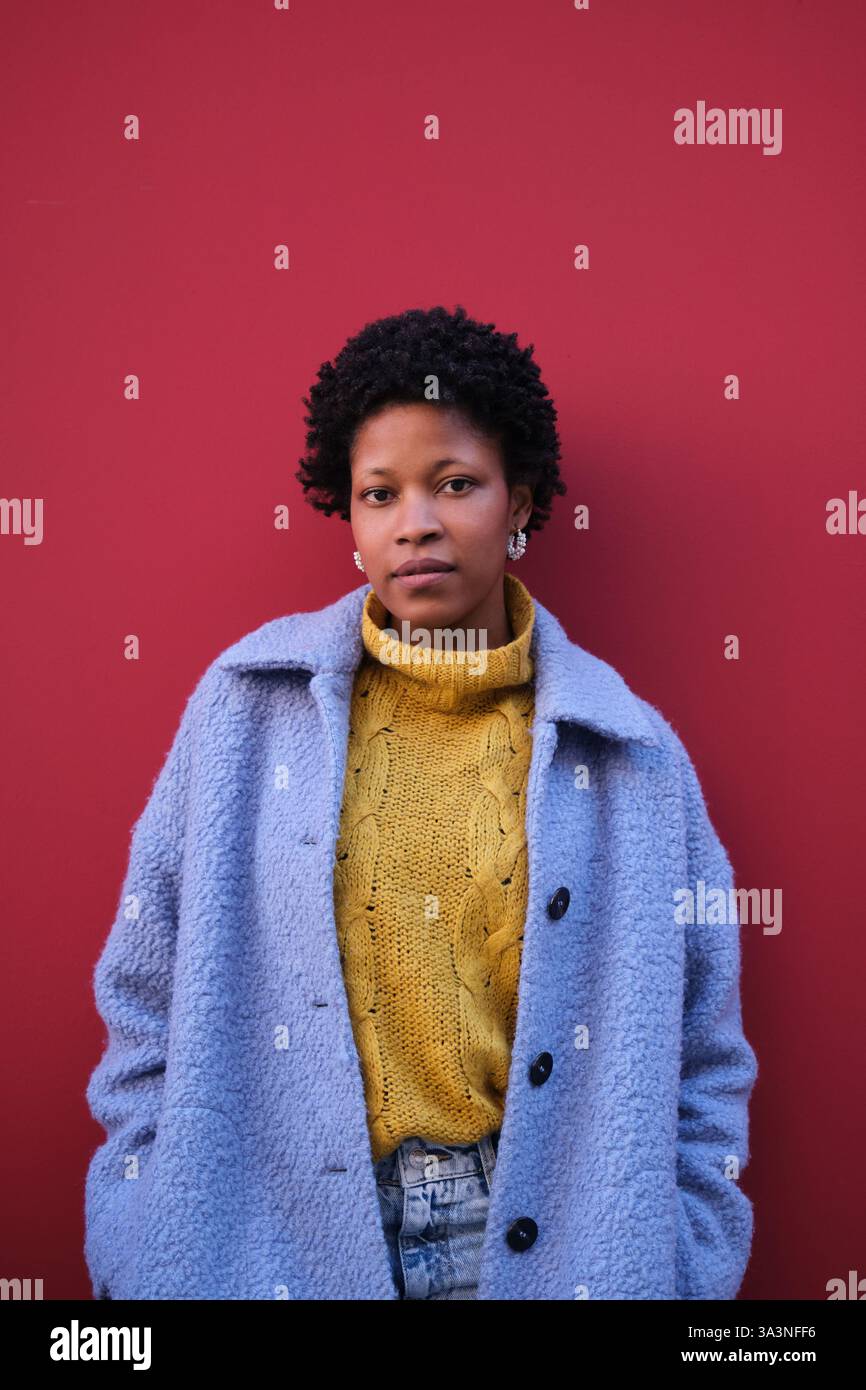 Jeune femme posant devant un mur rouge Banque D'Images