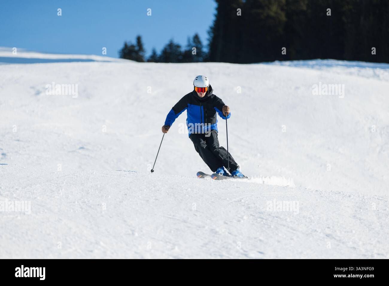 Skieur sculptant sur une pente enneigée à Kitzbühel sous un ciel bleu vif Banque D'Images