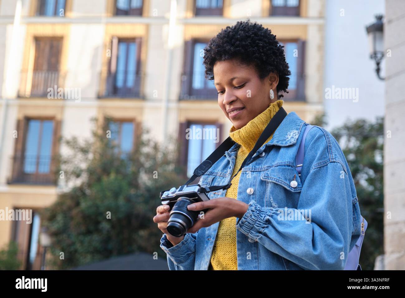 Femme souriante prenant des photos avec un appareil photo dans la ville Banque D'Images