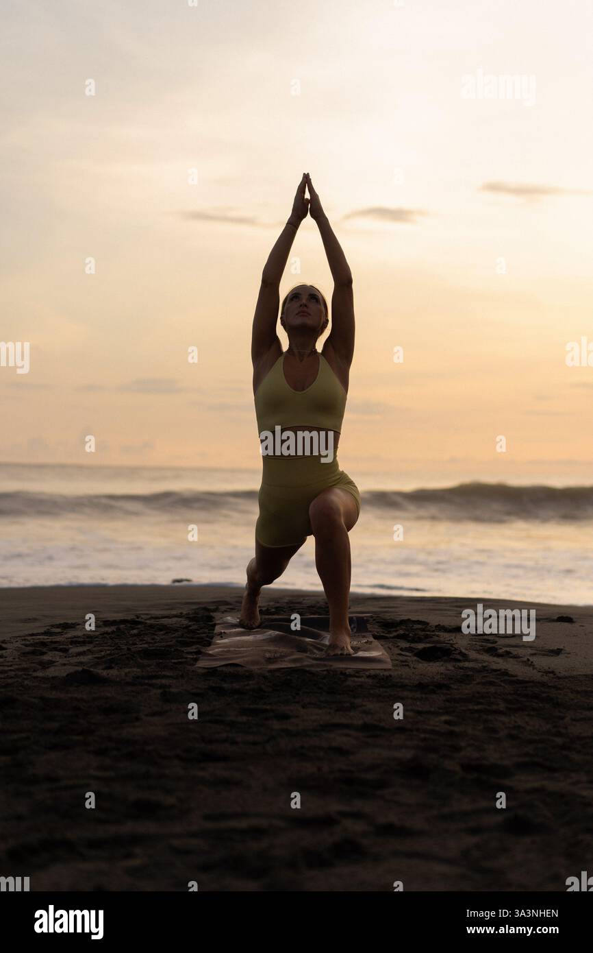 L'INDONÉSIE, Bali, woman practicing yoga sur la côte Banque D'Images
