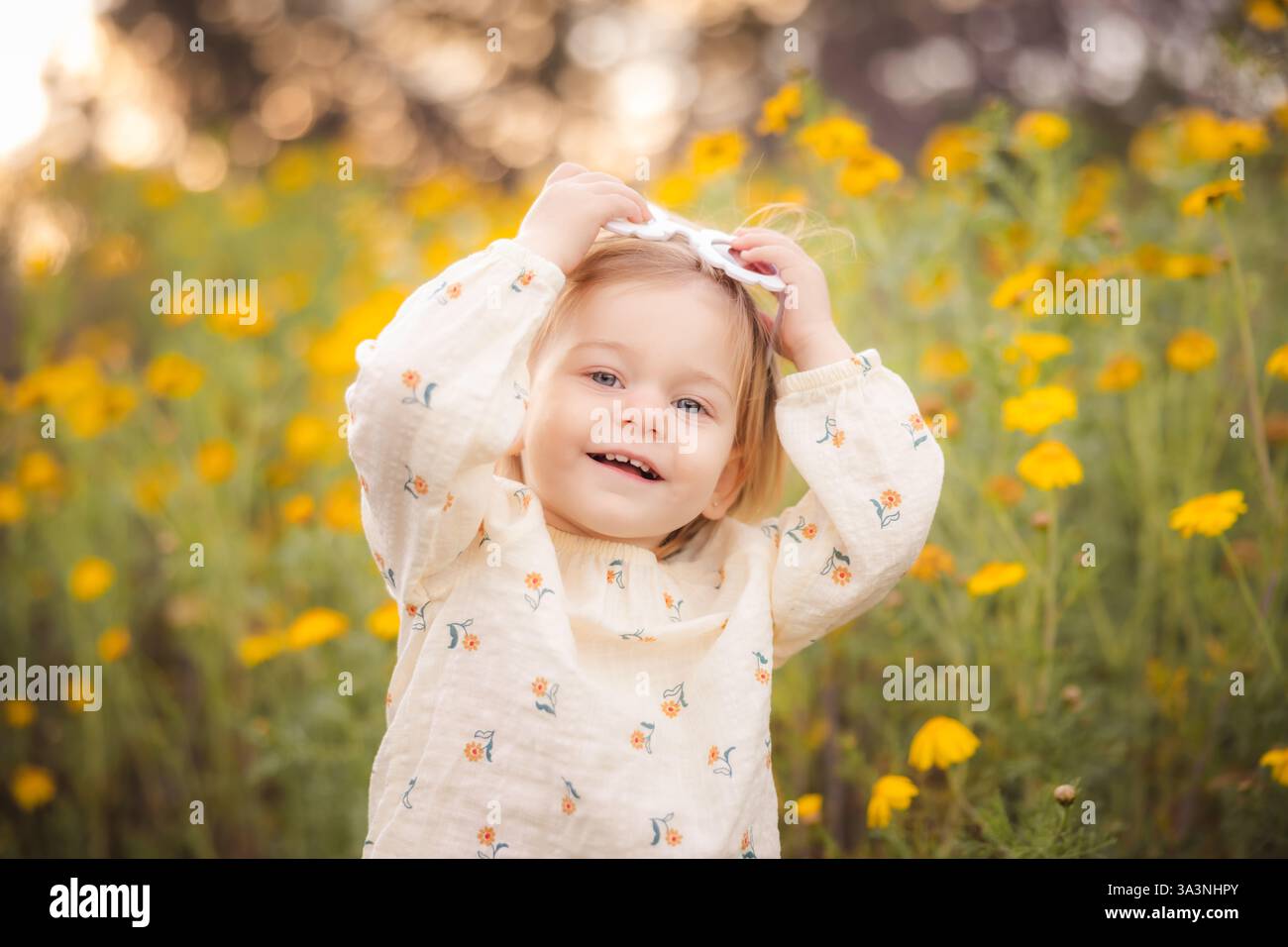 Fille souriant tout en tenant son verre de soleil de fleur sur le dessus de sa tête. Banque D'Images
