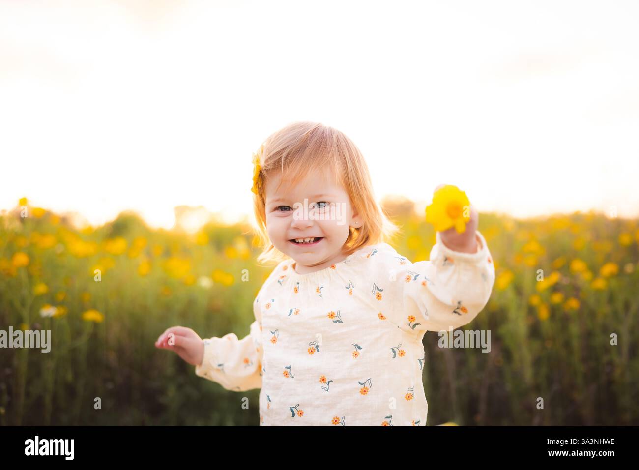 Enfant souriant tenant une fleur jaune. Banque D'Images