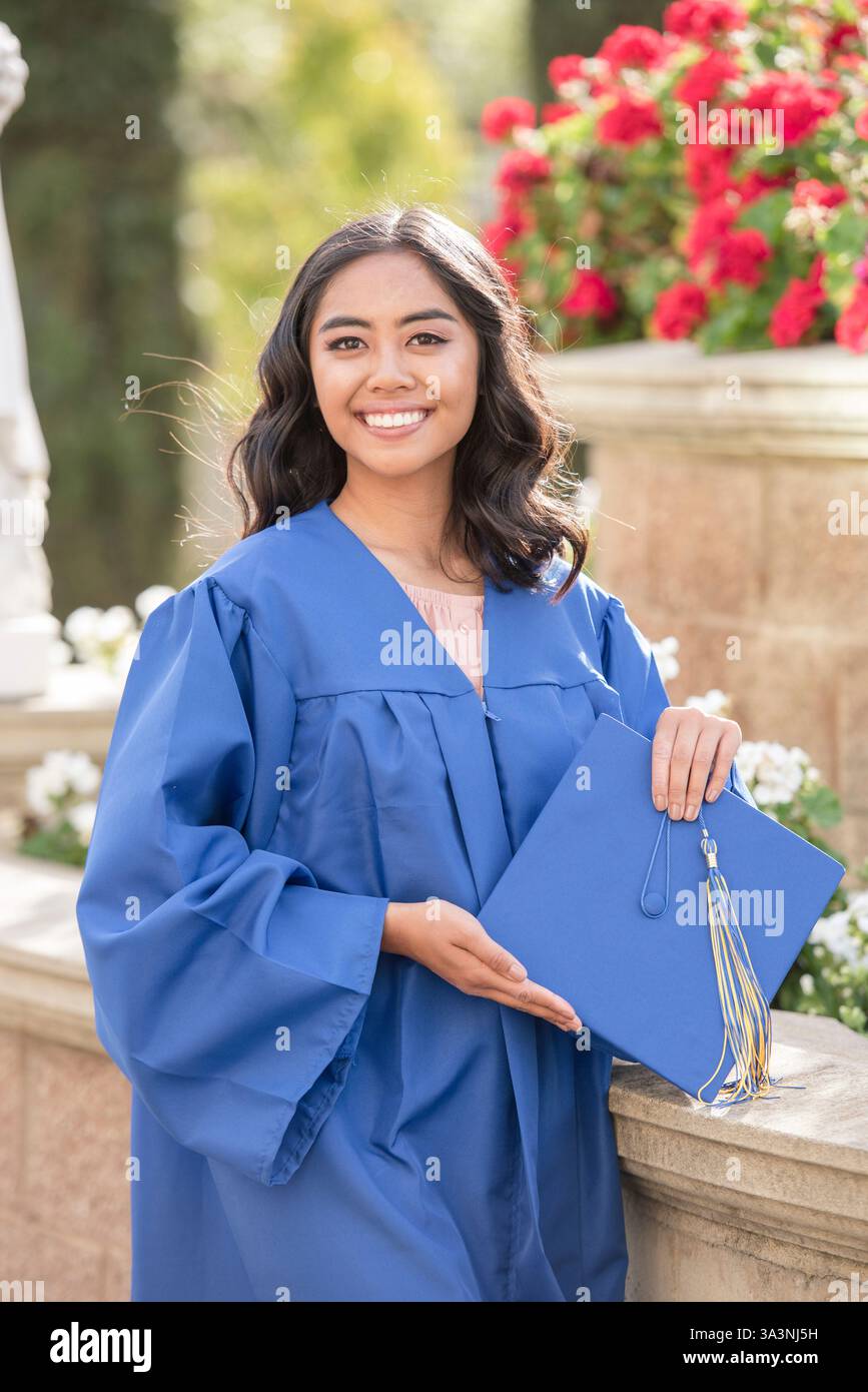 Fière diplômée du secondaire célèbre dans sa casquette et sa robe bleues Banque D'Images