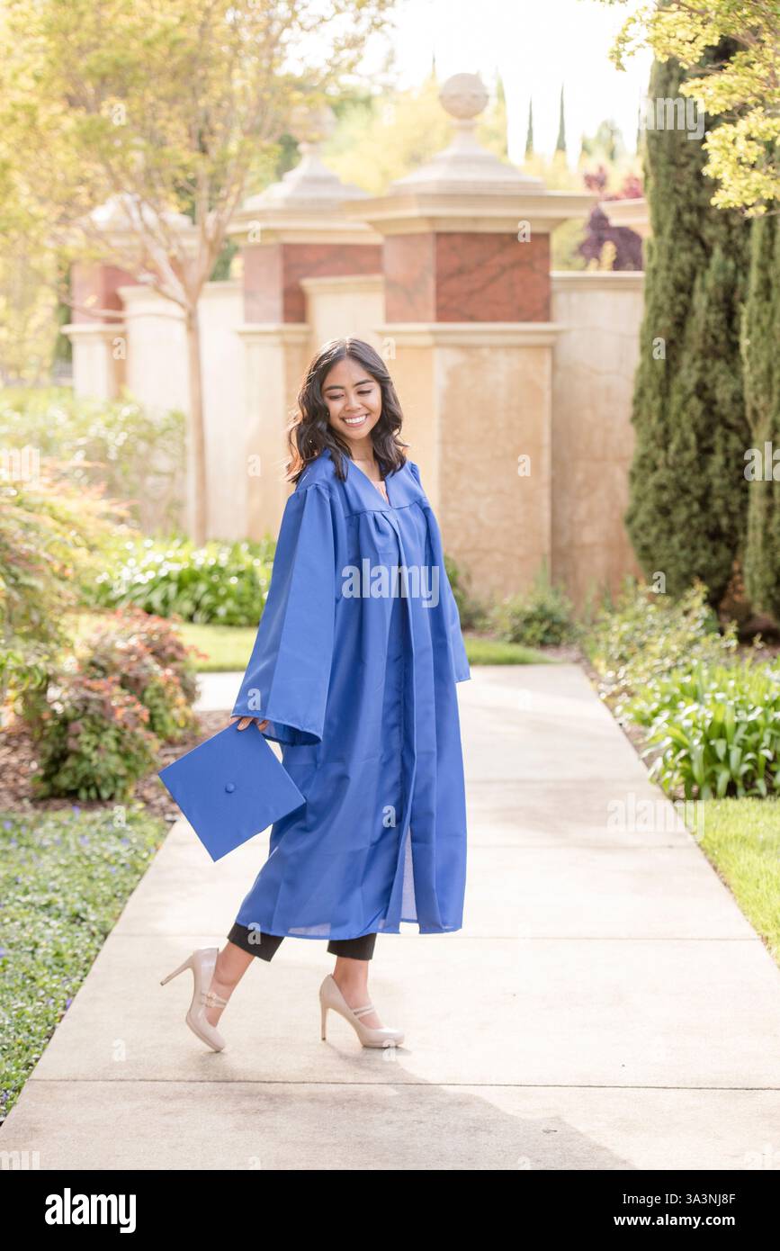 Diplômée tenant sa casquette et souriant Banque D'Images