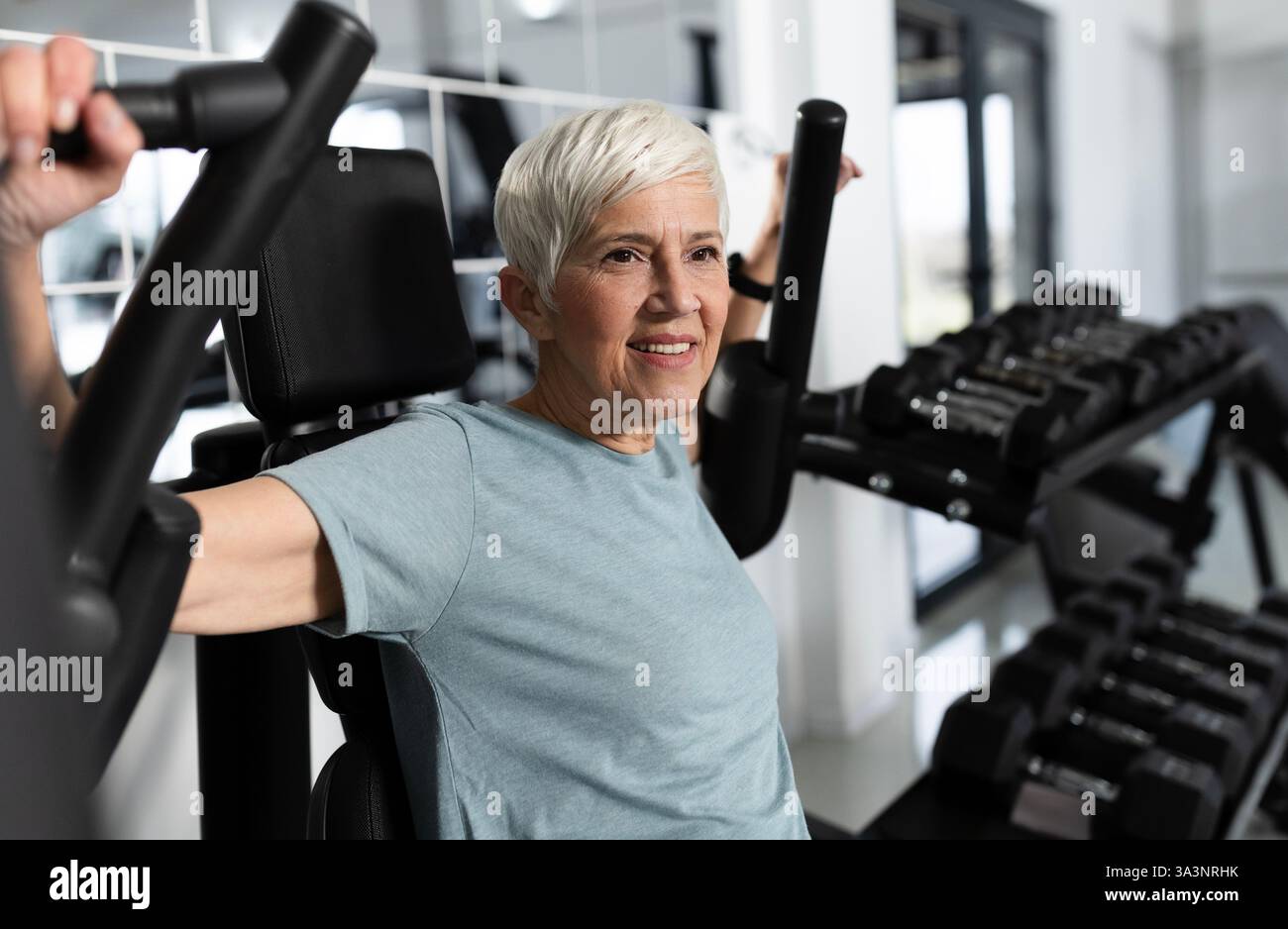 La participante fait de l'exercice au gymnase, en utilisant un équipement de musculation. Elle semble concentrée et déterminée pendant la routine d'exercice Banque D'Images
