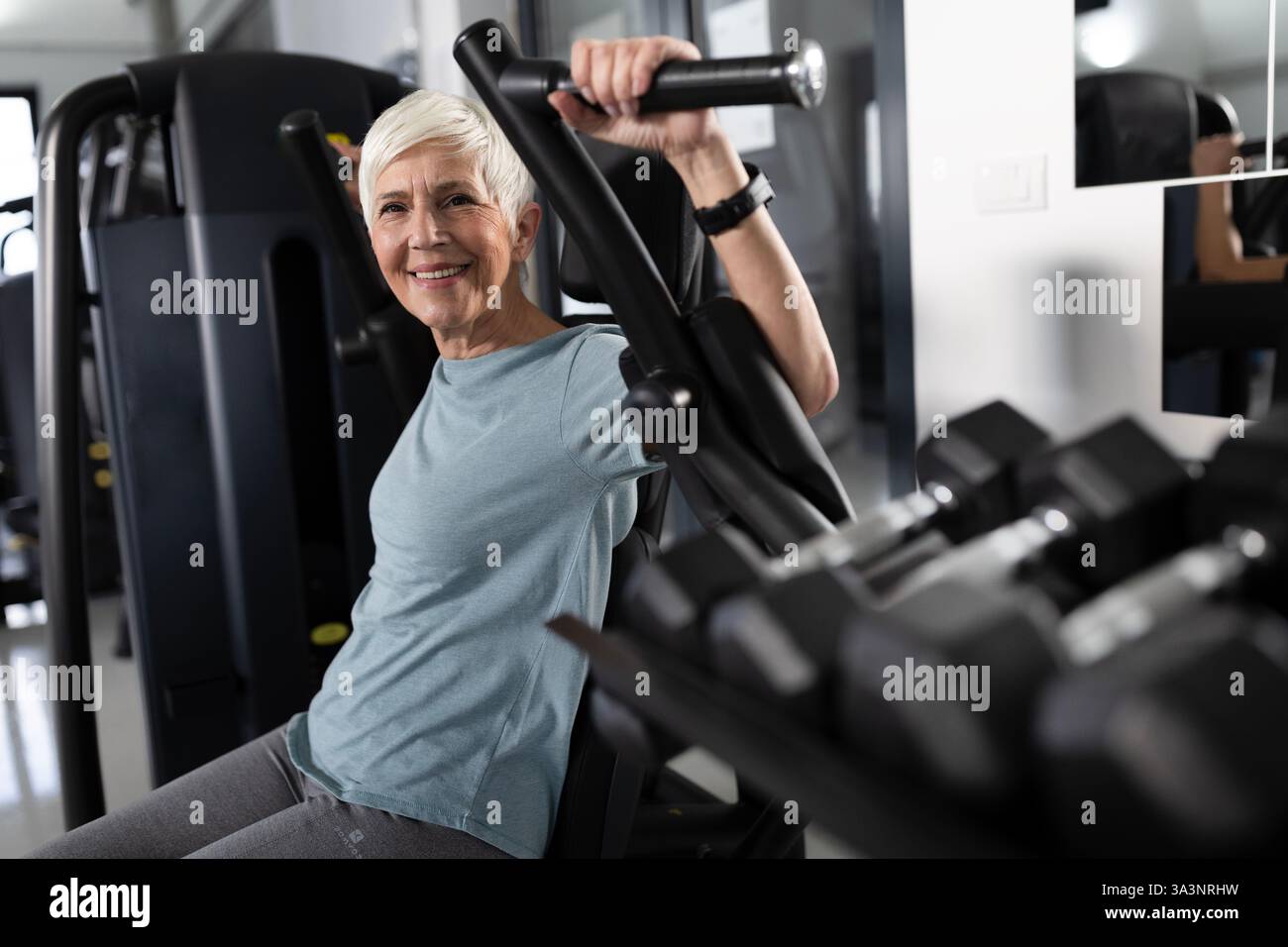 La participante fait de l'exercice au gymnase, en utilisant un équipement de musculation. Elle semble concentrée et déterminée pendant la routine d'exercice Banque D'Images