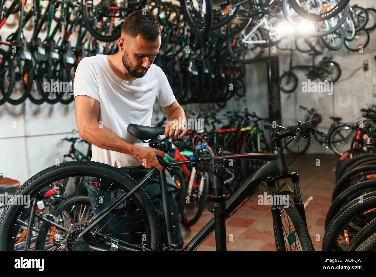 Réglages finaux. Réparateur homme dans le magasin de vélos, travaillant dans le magasin. Banque D'Images