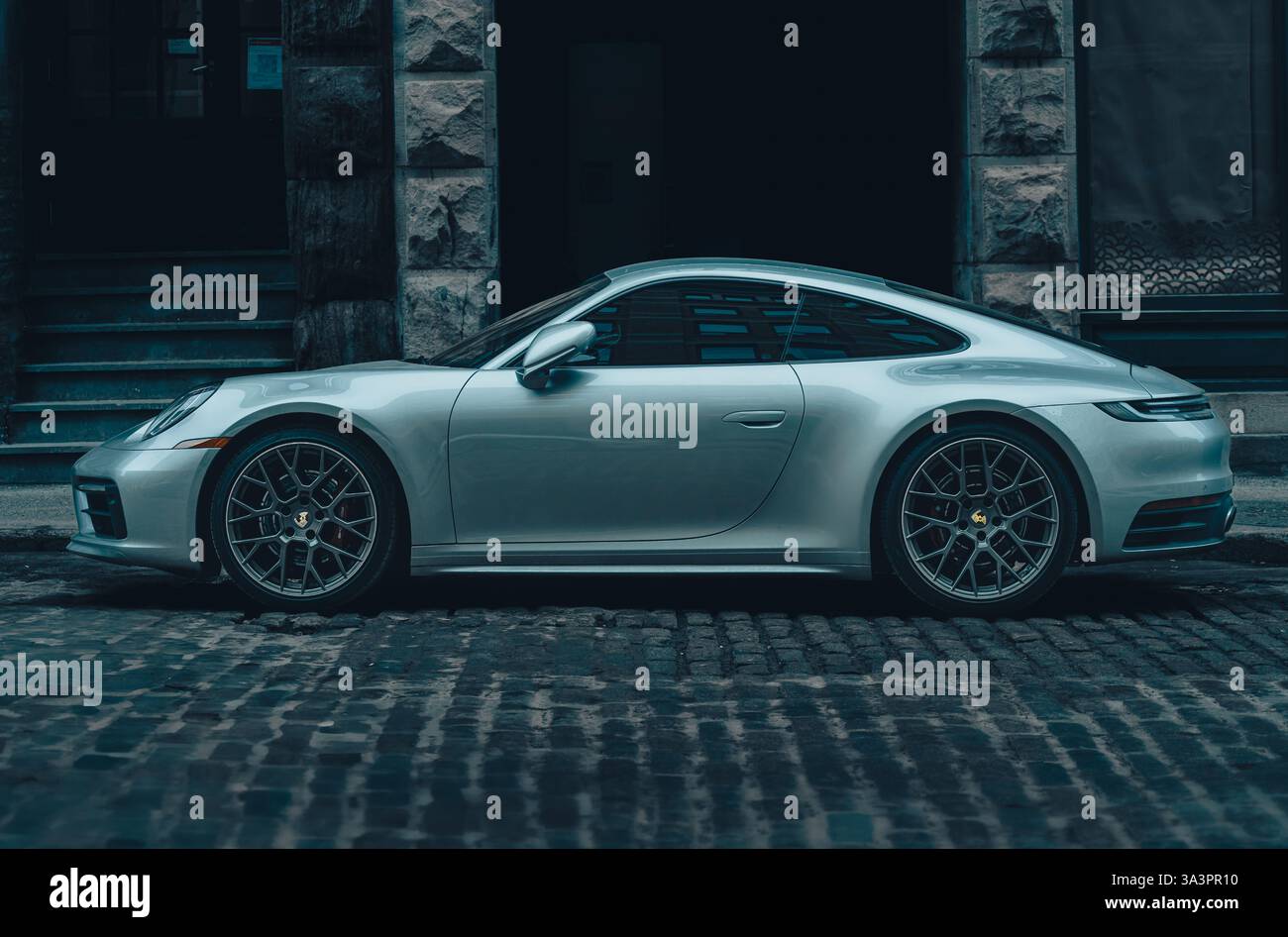 Une Porsche 911 argentée élégante garée sur une rue pavée, dégageant une élégance et des performances intemporelles. Banque D'Images