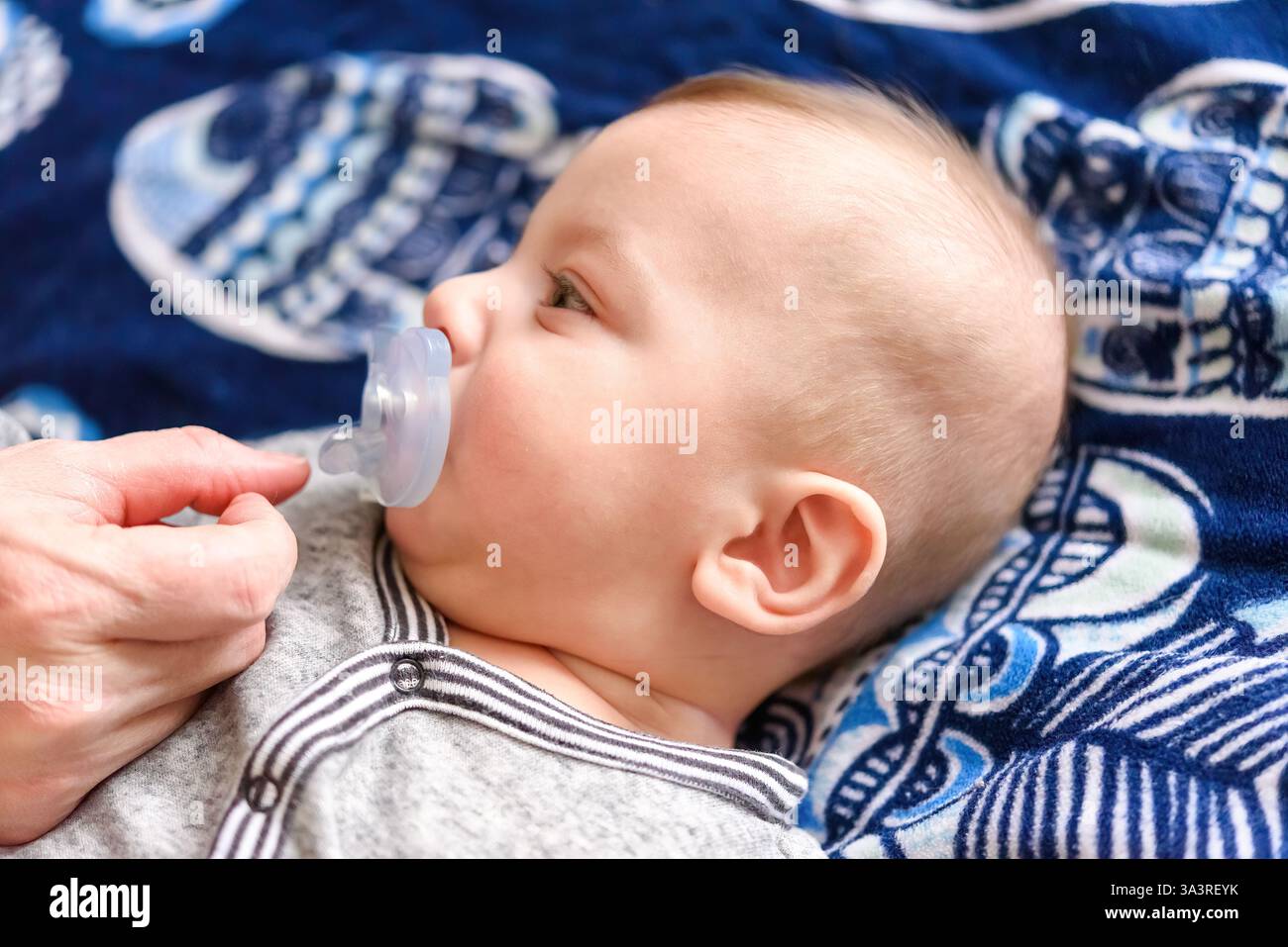 Bébé garçon allongé sur un lit avec une sucette Banque D'Images