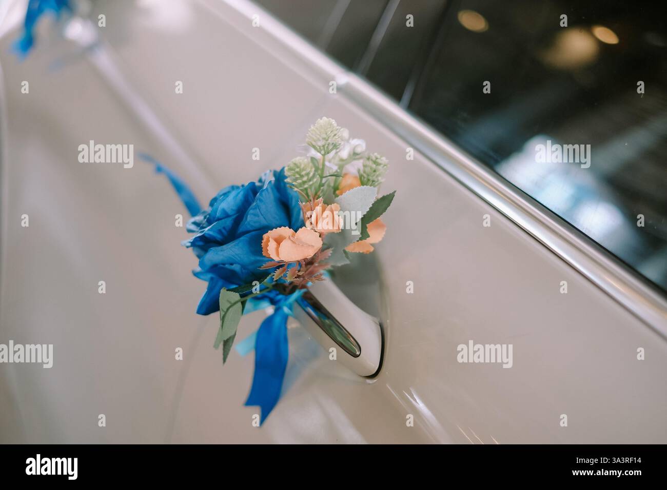 Gros plan de la poignée de porte d'une voiture d'époque décorée, ornée d'un arrangement floral frais. Cette touche festive ajoute de l'élégance à un mariage ou à un specia Banque D'Images