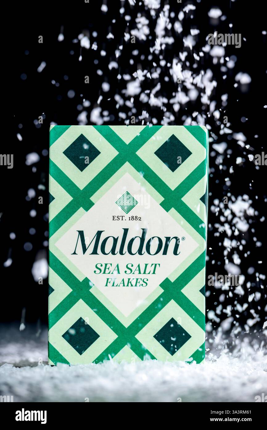 Boîte de flocons de sel de mer Maldon avec des flocons de sel tombant sur un fond noir, photo produit Banque D'Images