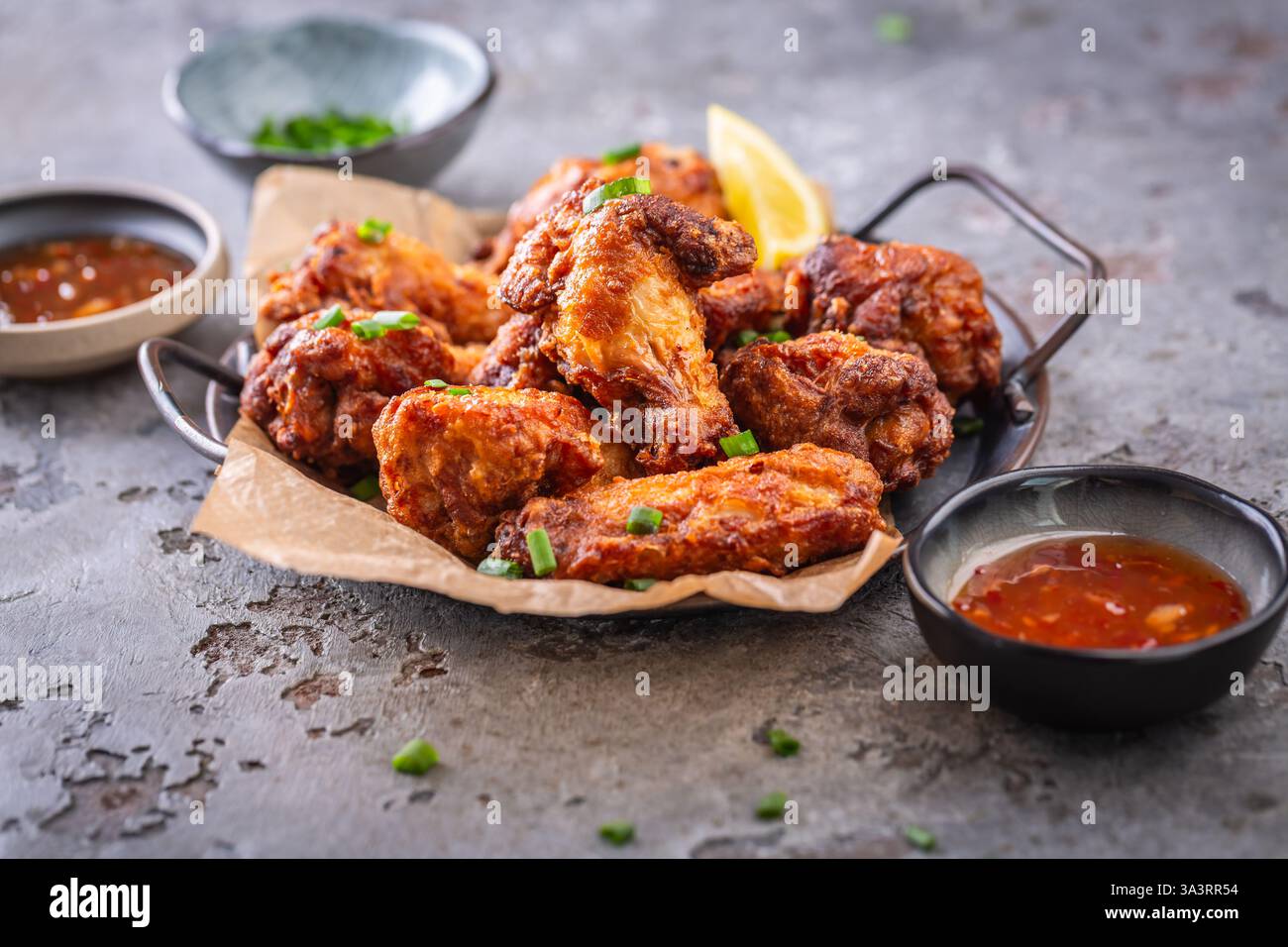 Ailes de poulet thaï épicées avec trempette chaude et oignons verts Banque D'Images