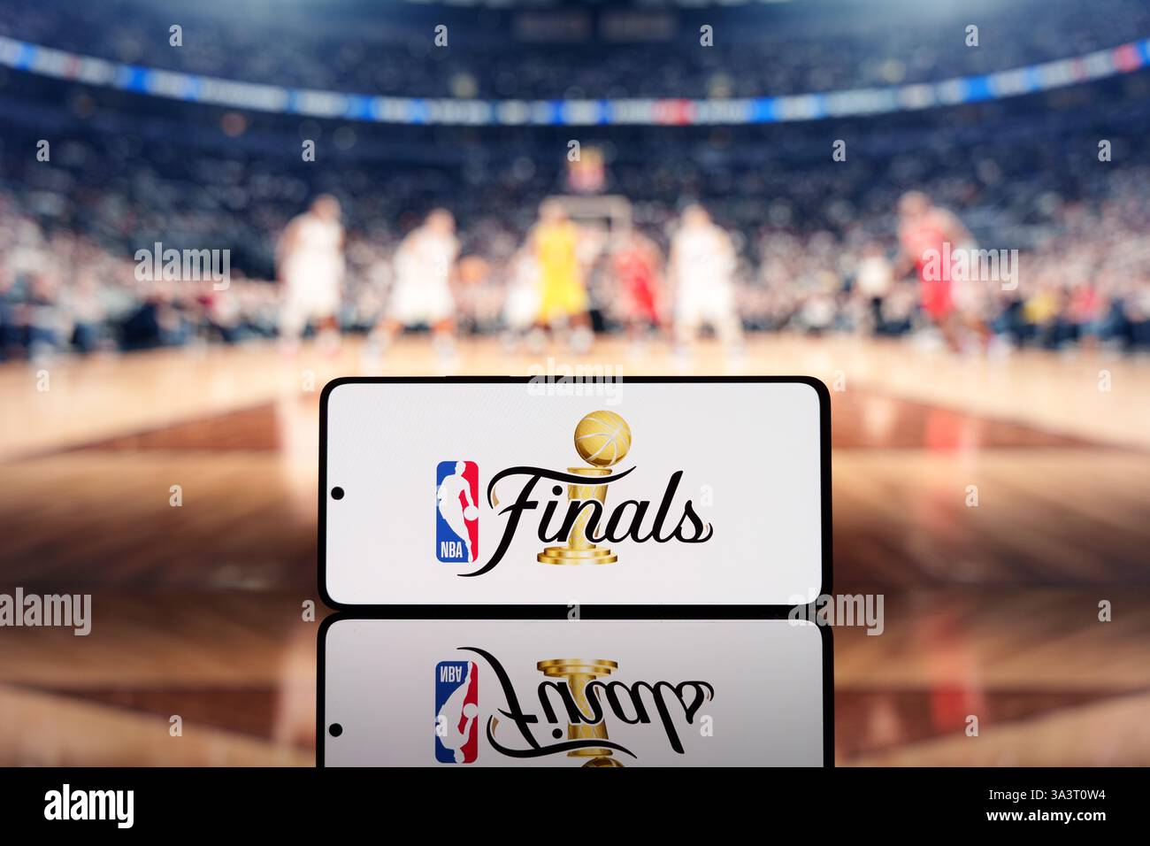 Smartphone affichant le logo des finales NBA avec un terrain de basket-ball flou et des joueurs en arrière-plan. Championnat de basket-ball et concept d'événement sportif Banque D'Images