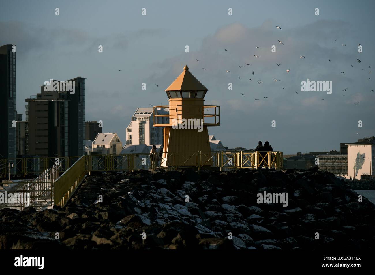 Phare jaune Hofoi un point de repère surplombant la baie de Faxaflói avec les gratte-ciel de la ville en arrière-plan. Banque D'Images