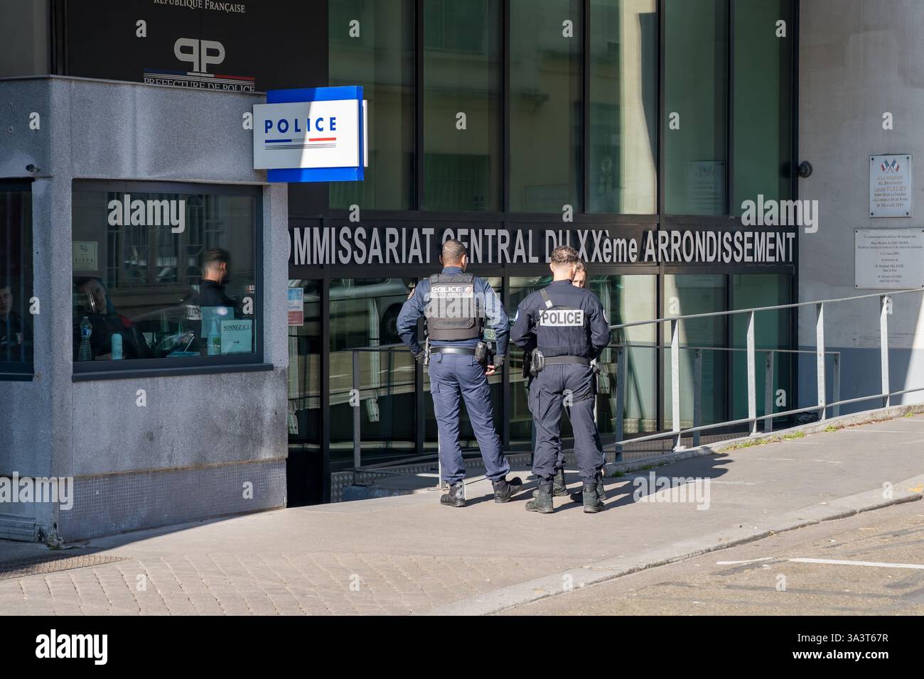 En fin d'après-midi, deux policiers engagent une conversation devant un poste de police central dans un quartier urbain animé Banque D'Images