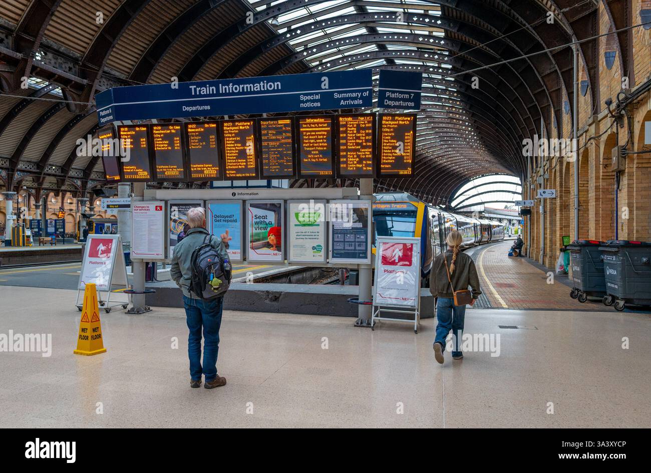 Passagers regardant les horaires du train sur un grand écran électronique à la gare de york. Banque D'Images