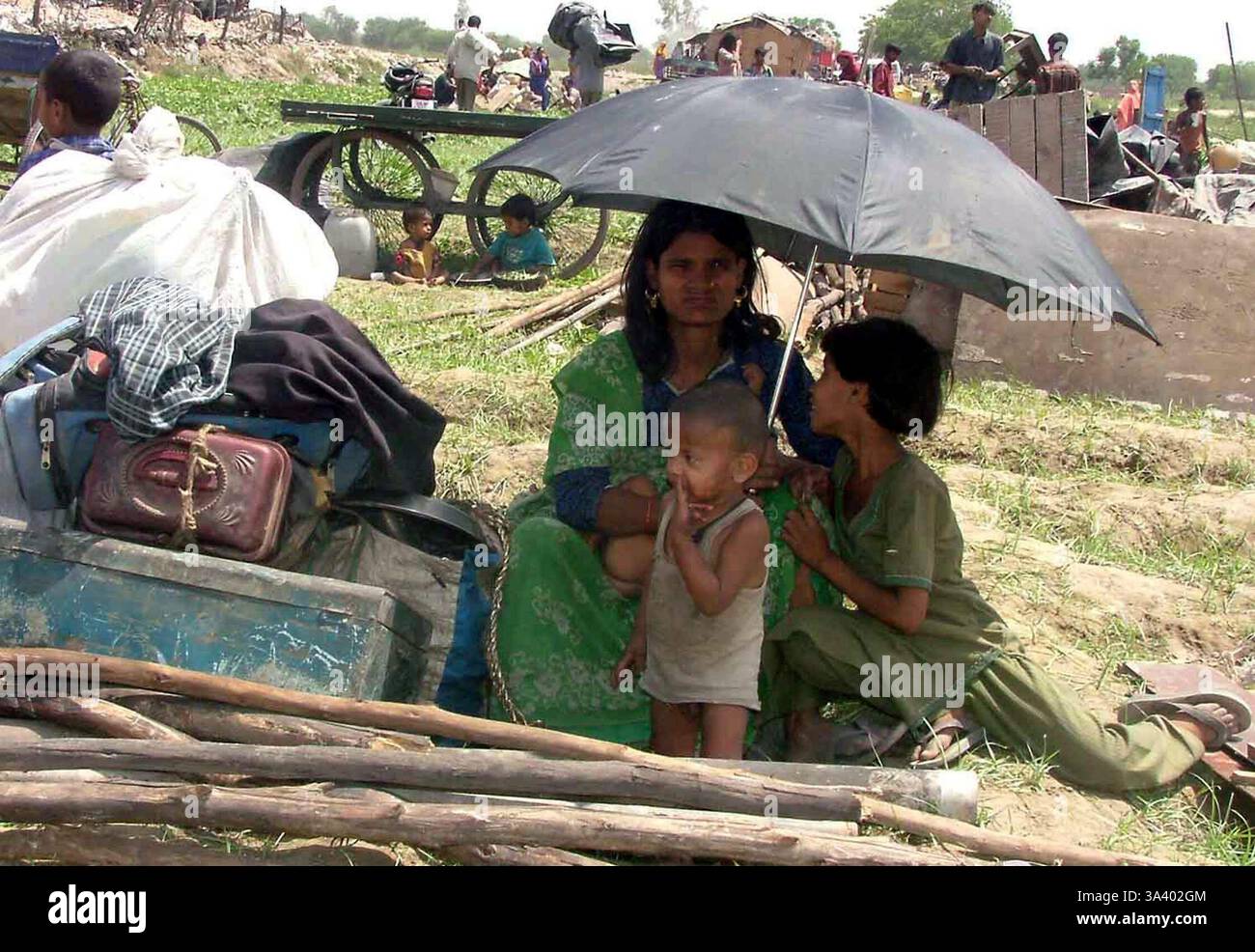 12 avril 2004 ; New Delhi, INDE ; Une femme est assise avec ses enfants et sa maison tient dans une zone ouverte après un incendie dans sa cabane dans un bidonville de New Delhi le 12 avril 2004. L'incendie a détruit au moins 2 500 baraques dans un bidonville de New Delhi. La plupart des gens qui y vivent sont des ouvriers et des petits hommes d'affaires qui sont venus d'autres états indiens espérant un avenir meilleur. Banque D'Images
