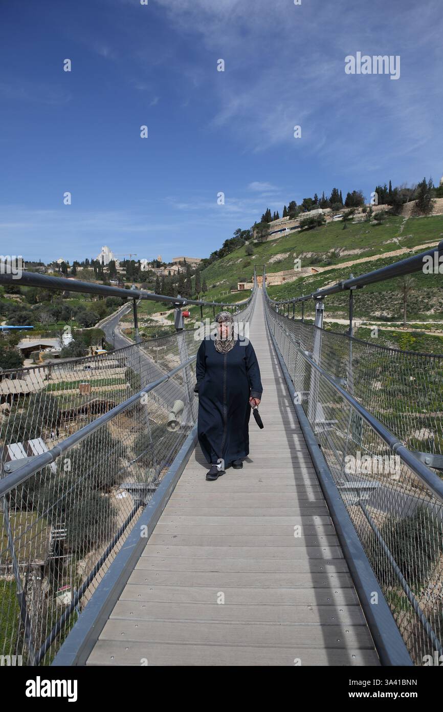 Une femme musulmane âgée portant le Hijab marche sur le pont suspendu de la vallée de Hinnom qui traverse la vallée de Hinnom du mont Sion à Abu Tor. . Banque D'Images