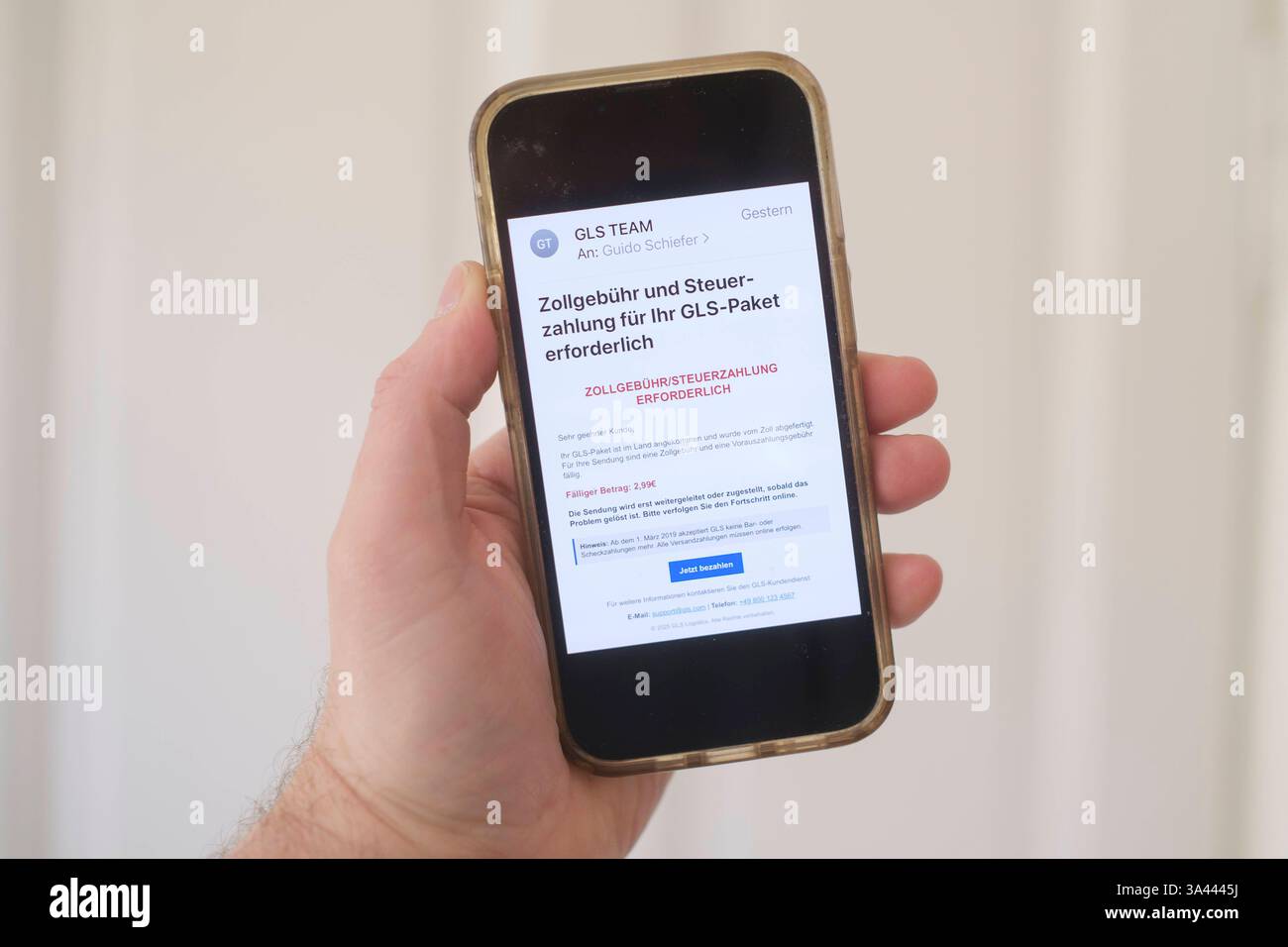 Hand mit Mobiltelefon auf dem eine betrügerische Email zu sehen ist, die eine angebliche Zollgebühr bzw Steuernachzahlung für ein Paket einfordert. *** Main avec un téléphone portable montrant un courriel frauduleux exigeant un prétendu paiement de frais de douane ou de taxes pour un colis. Nordrhein-Westfalen Deutschland, Allemagne GMS18788 Banque D'Images