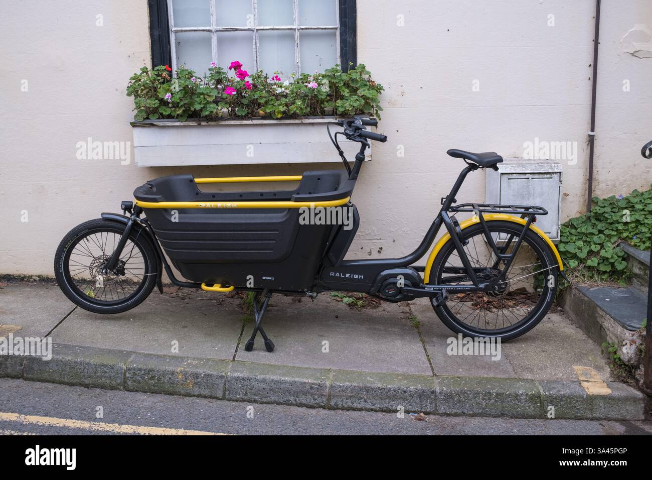 Vélo cargo Raleigh Stride 2 noir et jaune garé sur le trottoir devant un magasin à Salcombe, Devon Banque D'Images