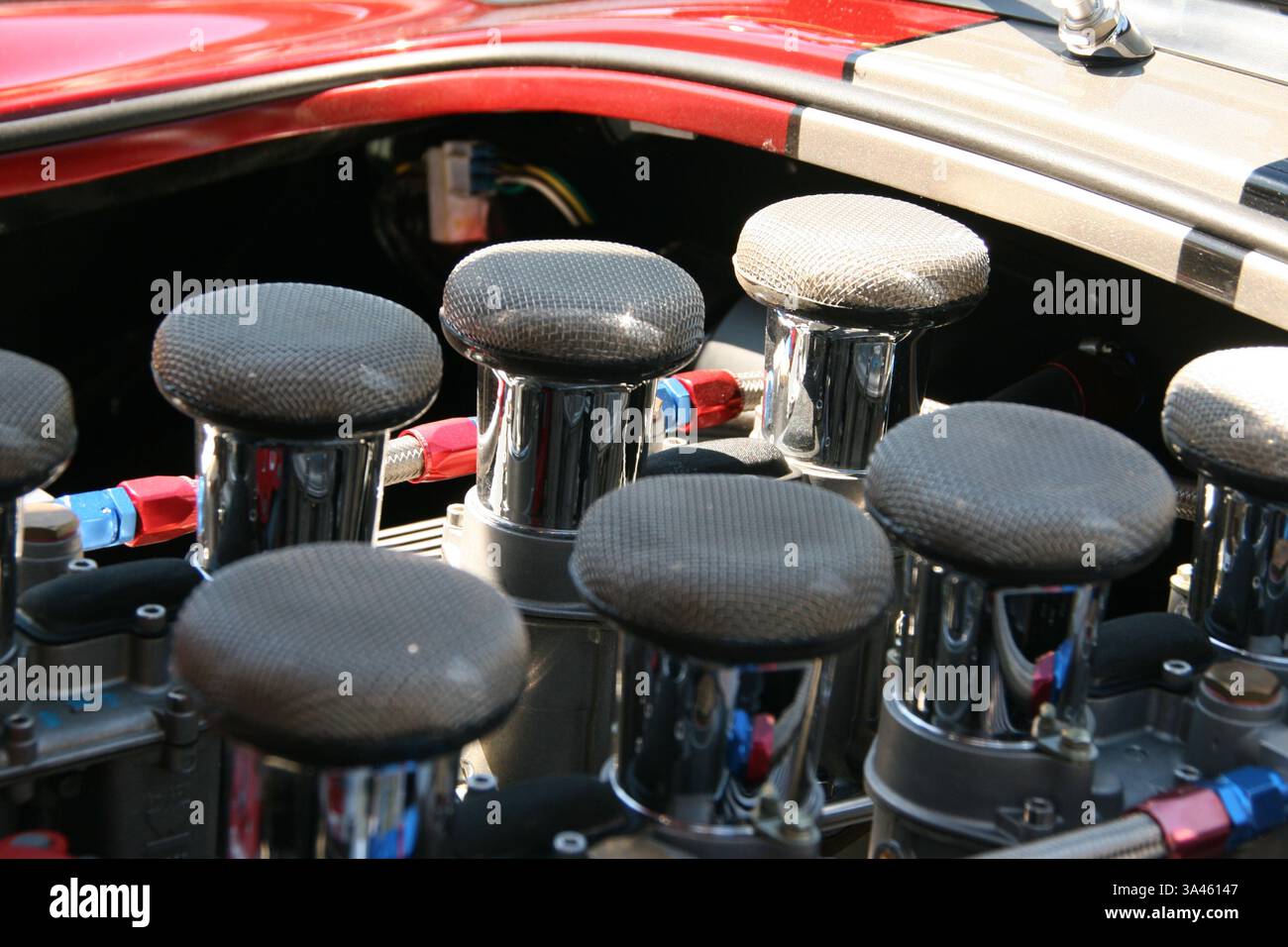 Huit tubes d'admission chromés individuels sur un moteur V-8 dans une voiture de sport rouge et blanche classique. Banque D'Images
