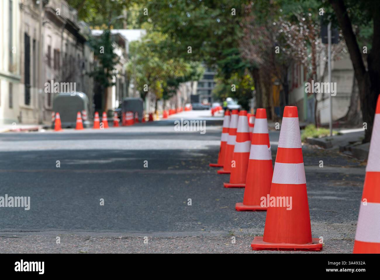 Cônes de circulation orange et blanc bordant une rue vide de la ville, créant une barrière pour les véhicules Banque D'Images