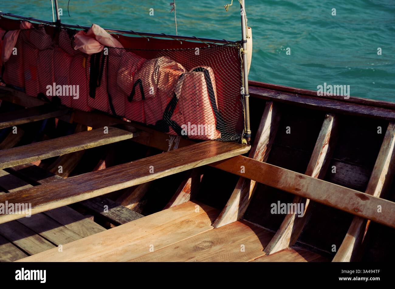 L'intérieur rustique d'un bateau traditionnel thaïlandais à longue queue, avec des planches en bois, des banquettes simples et des gilets de sauvetage rangés dans un filet en maille Banque D'Images L'intérieur rustique d'un bateau traditionnel thaïlandais à longue queue, avec des planches en bois, des banquettes simples et des gilets de sauvetage rangés dans un filet en maille Banque D'Images
