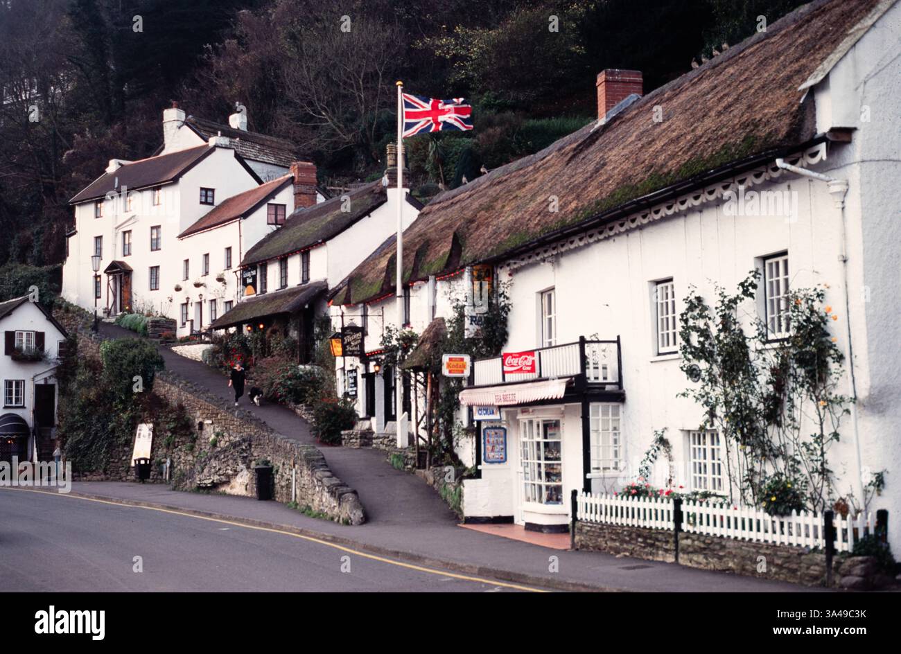 Une femme promène son chien dans le village pittoresque de Lynmouth, Devon, tôt le matin. Banque D'Images