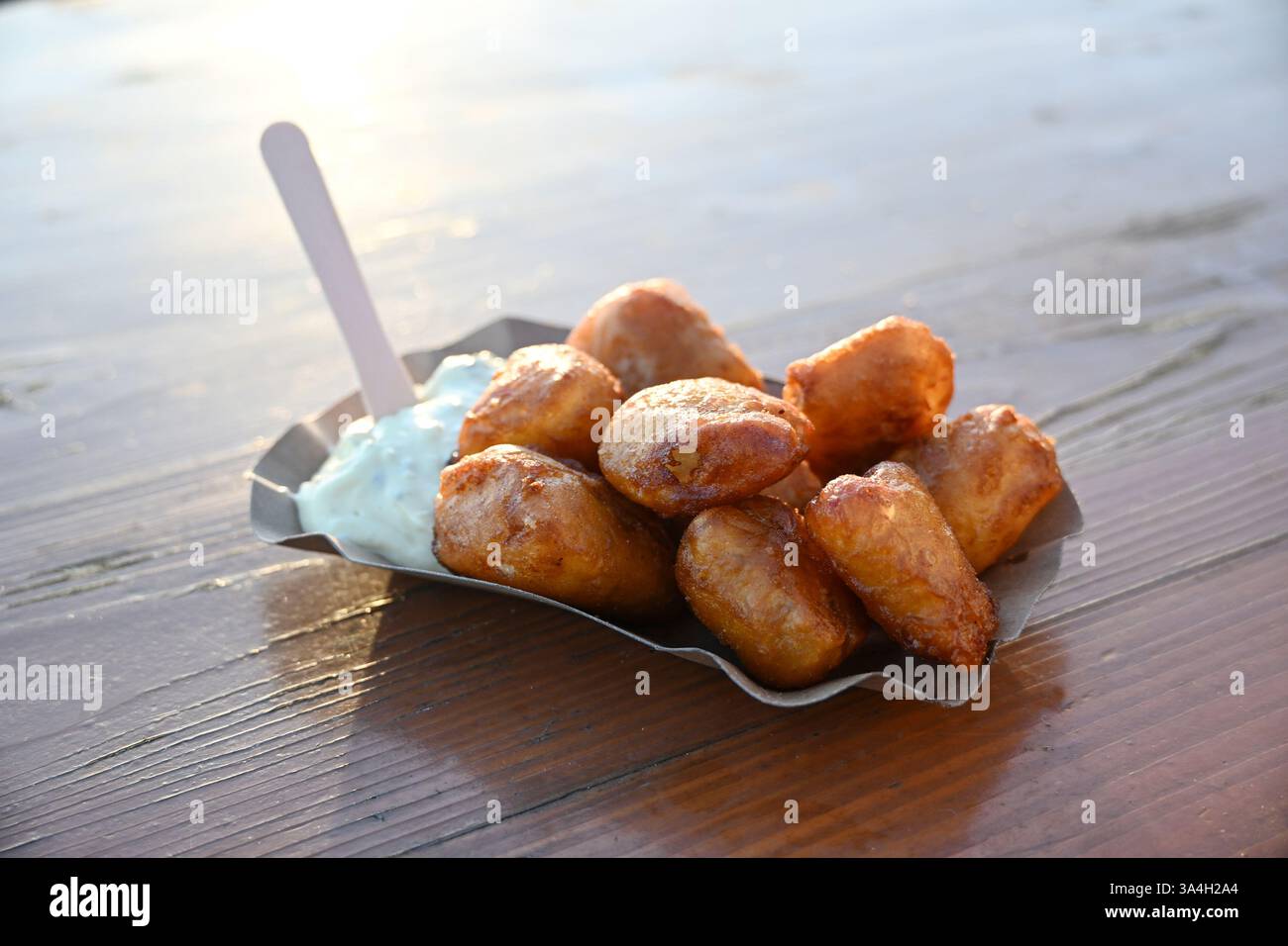 Morue frite enveloppée dans de la pâte à frire avec sauce remoulade sur une assiette en carton, fruits de mer côtiers, plat de poisson à emporter à un grill sur le port, espace copie Banque D'Images