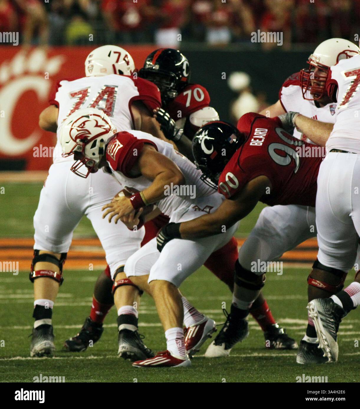 20 septembre 2014 - Cincinnati, Ohio, U. S - Miami (OH) le quarterback des Redhawks Andrew Hendrix (12) est abattu par Cincinnati Bearcats Defensive Tackle Camaron Beard (90) dans le premier quart de jeu le samedi 20 septembre 2014 pendant le match à Paul . Brown Stadium. (Crédit image : © Ernest Coleman/ZUMA Wire) Banque D'Images