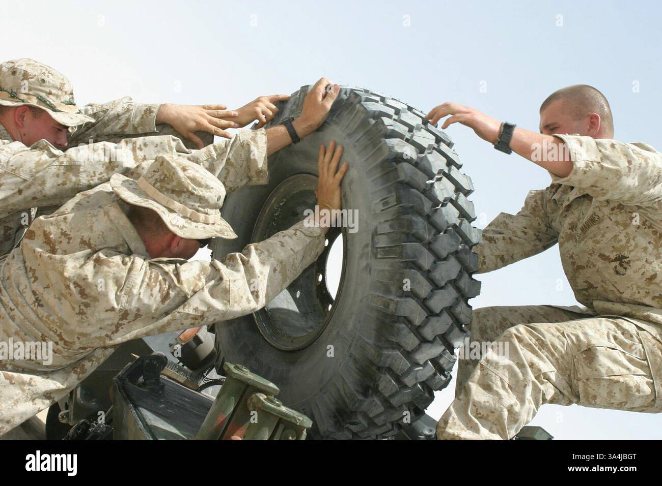 12 juillet 2004 ; Central, Koweït ; Marines avec la 24e Marine Expeditionary Unit lève un gros pneu gonflé au sommet de leur véhicule blindé léger. Le pneu est une réserve à utiliser en cas de crevaison. Les Marines sont avec Light Armored reconnaissance Platoon attaché à la compagnie d'armes, 1er bataillon 2nd Marines. Le MEU est arrivé au Koweït pour commencer l'acclimatation et la formation complémentaire avant de partir pour leur destination en Iraq. Banque D'Images