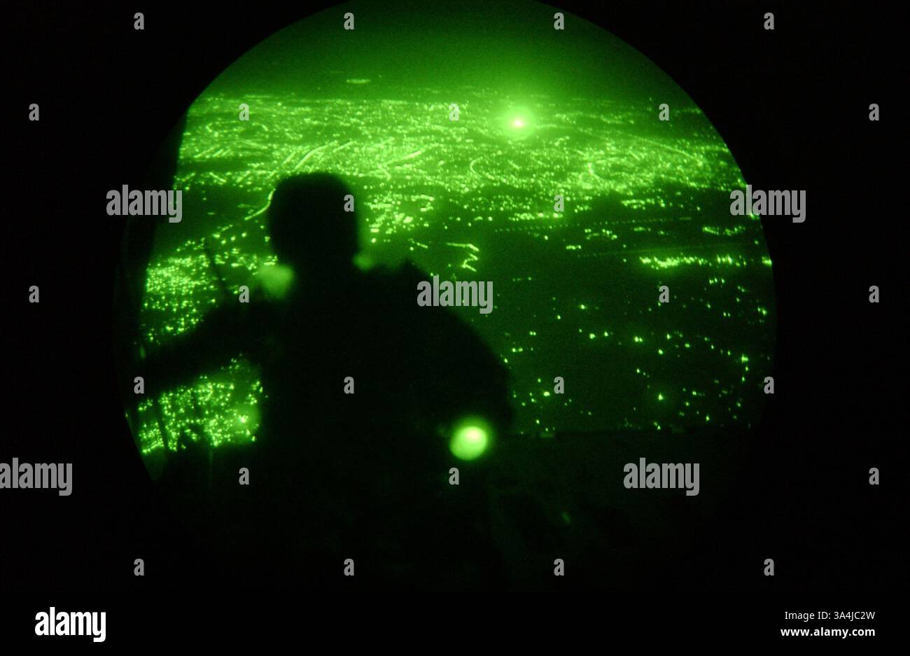 23 juillet 2004 ; Bagdad, Irak ; le Sgt-maître TODD SMALENBERG, maître de saut principal, 1er Bataillon de reconnaissance, I Marine Expeditionary Force, observe la vue de Bagdad tard dans la nuit depuis l'arrière du KC-130 Hercules. Le sauteur de 39 ans d'Oscoda, Mich., et quatre autres Marines de reconnaissance ont sauté de l'avion cargo et sont entrés dans l'histoire le 23 juillet pour le premier parachute d'ouverture à haute altitude au combat pour le corps des Marines. Banque D'Images