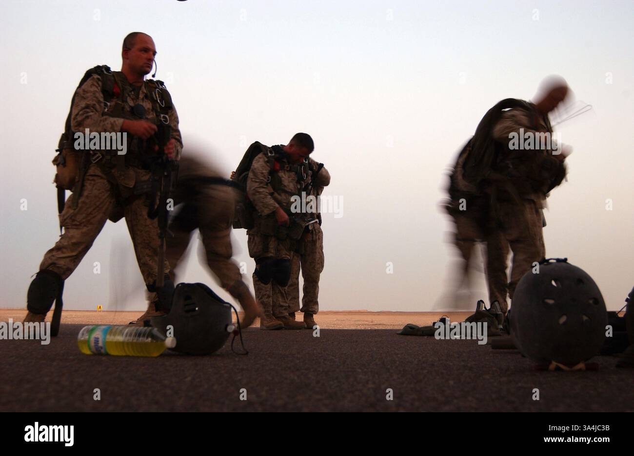 23 juillet 2004 ; Al Taqaddum, Irak ; Un groupe de parachutistes du 1er Bataillon de reconnaissance, I Marine Expeditionary Force, se précipitent pour préparer leurs packs et parachutes pour un parachute de haute altitude à partir d'un avion cargo Marine KC-130 Hercules. Les Pathfinders sont devenus les premiers Marines à effectuer un saut d'ouverture en haute altitude au combat le 23 juillet dans une zone de largage près de Bagdad. La mission des Pathfinders était de marquer un DZ pour un groupe de Marines de reconnaissance largués à basse altitude par deux CH-46E Sea Chevaliers. Banque D'Images