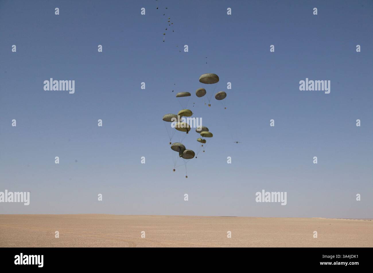 09 août 2004 ; Camp Korean Village, Irak ; largué d'un avion cargo KC-130 du Marine Aerial Refueler transport Squadron 352, des paquets de rations parachute au sol du désert à l'extérieur du Camp Korean Village, Irak, lors d'une mission de ravitaillement aérien le 9 août 2004. En utilisant des parachutes militaires standard, les avions cargo doivent voler à des altitudes plus basses pour assurer des largages précis, mais sont plus sensibles aux tirs ennemis. Avec le Sherpa, un système de parachute produit commercialement et guidé par le Global Positioning System qui peut se diriger de près de cinq miles de haut à moins de 200 mètres d'un point de chute ciblé, mil Banque D'Images