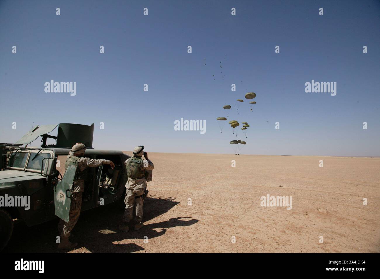 09 août 2004 ; Camp Korean Village, Irak ; les Marines du 1er peloton de livraison aérienne regardent flotter des paquets de rations au sol du désert à l'extérieur du Camp Korean Village, Irak, lors d'une mission de ravitaillement aérien le 9 août 2004. En utilisant des parachutes militaires standard, les avions cargo doivent voler à des altitudes plus basses pour assurer des largages précis, mais sont plus sensibles aux tirs ennemis. Avec le Sherpa, un système de parachute produit commercialement et guidé par le Global Positioning System qui peut se diriger de près de cinq miles de haut à moins de 200 mètres d'un point de largage ciblé, les avions militaires peuvent larguer des approvisionnements à partir de s. Banque D'Images