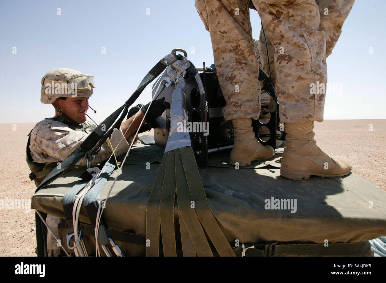 09 août 2004 ; Camp Korean Village, Irak ; les gréeurs de parachutistes marins du 1er peloton de livraison aérienne, le Cpl DOUGLAS F. MILLER, à gauche, et le Cpl CHRIS KADOLPH, commencent à détacher un système de parachute cargo de précision Sherpa du sommet d'un paquet de rations près du Camp Korean Village, Irak, le 9 août 2004. Deux systèmes Sherpa ont fait leurs premiers vols et atterrissages de précision dans une zone de combat le 9 août. Le Sherpa est un système produit commercialement guidé par le système de positionnement global qui peut se diriger de près de cinq miles de haut à moins de 200 mètres d'un point de chute ciblé. Le peloton, qui est la partie O. Banque D'Images