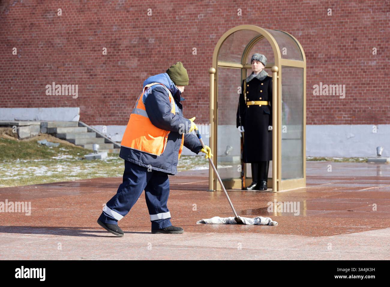 Femme concierge nettoyer la rue près du soldat russe de la garde d'honneur près du mur du Kremlin à Moscou Banque D'Images