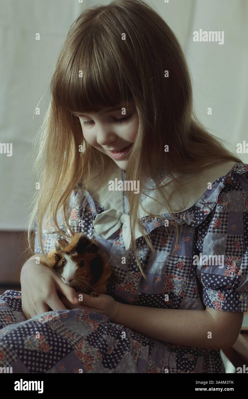 Petite fille tenant un cochon d'Inde, portrait de style vintage Banque D'Images