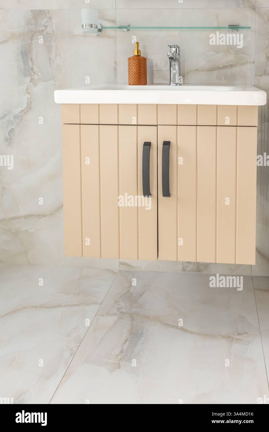 Une salle de bain avec une armoire en bois à deux portes. Mobilier de salle de bains dans l'appartement moderne. Carrelage en céramique. Salle de bains avec comptoir en bois. Personne, cl Banque D'Images